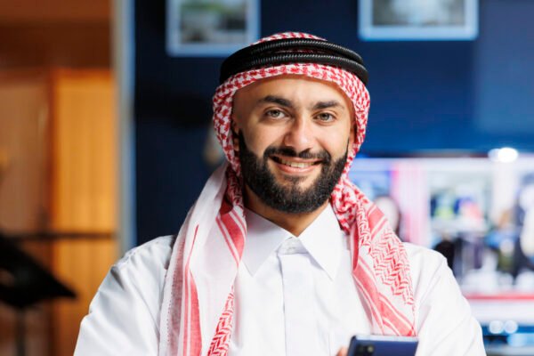 Smiling Muslim guy holding a cell phone