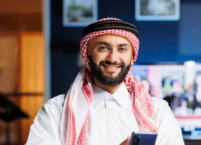 Smiling Muslim guy holding a cell phone Smiling Muslim guy holding a cell phone